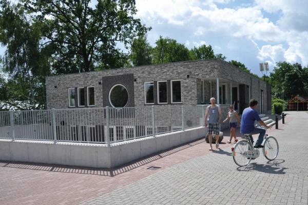Campeggio Papillon Country Resort con un edificio, persone che camminano e un ciclista su un sentiero lastricato.