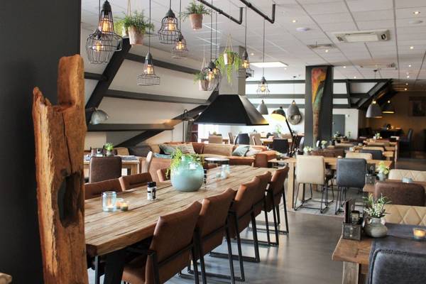 Innenbereich eines Restaurants mit Holztischen und Metallleuchten