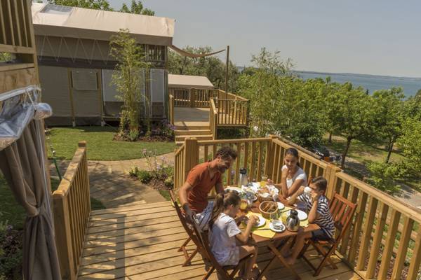 Familie spiser morgenmad på terrasse ved camping Plaani di Clodia.