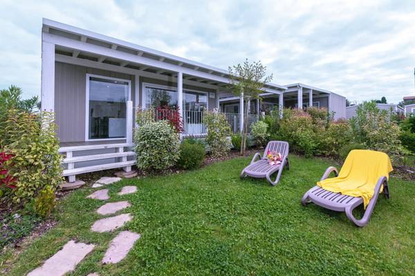 Udvendigt udseende af en camping med et hus og to liggestole på en græsplæne