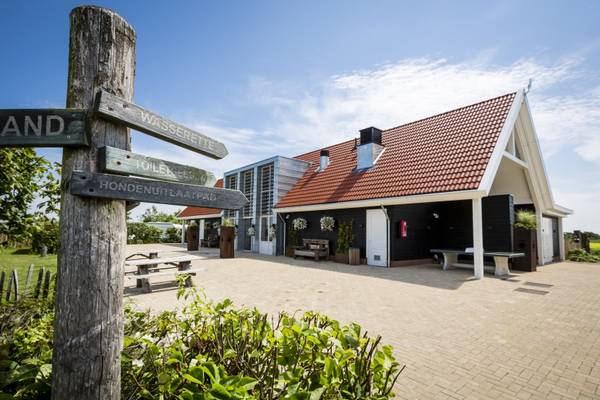 Campingplatz Strandpark De Zeeuwse Kust mit Gebäude, Bänken und Schildern.