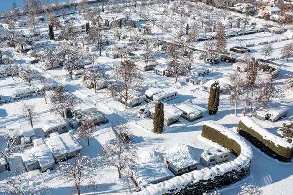 Vista aerea di un campeggio innevato con molte roulotte e alberi ricoperti di neve.