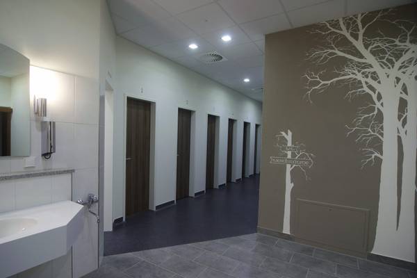 Interior de las instalaciones sanitarias del camping Strandcamping Waging am See con azulejos grises y paredes blancas.