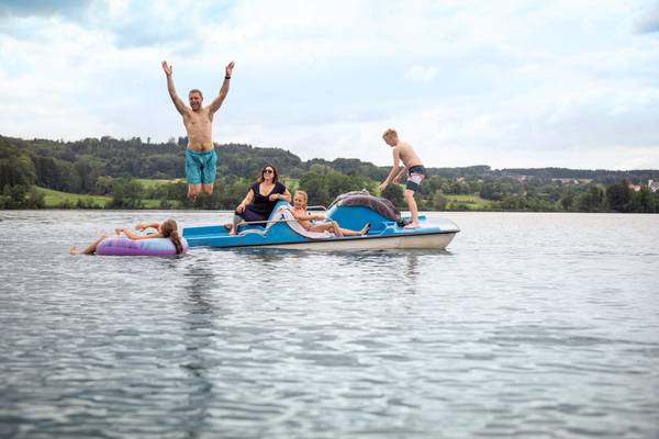 Familia en un bote en el lago, uno salta al agua