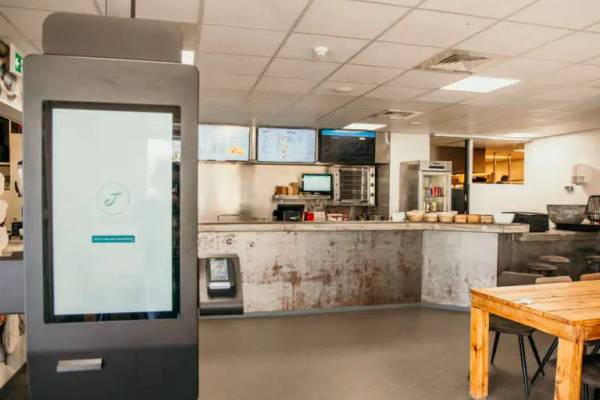 Innenbereich eines Cafés im Campingplatz Strandpark De Zeeuwse Kust mit Monitor und Holztisch.