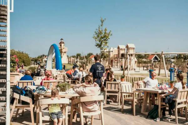 Outdoor-Cafe im Strandpark De Zeeuwse Kust mit sitzenden und spielenden Menschen.