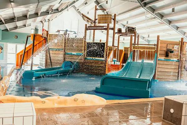Ein Hallenwasserpark im Campingplatz mit Rutschen und Wasserspielbereich.