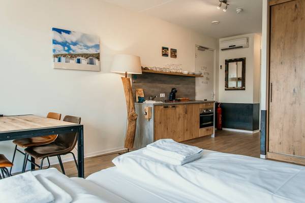 Innenbereich des Campingplatzes Strandpark De Zeeuwse Kust mit Bett, Tisch und Küchenzeile.
