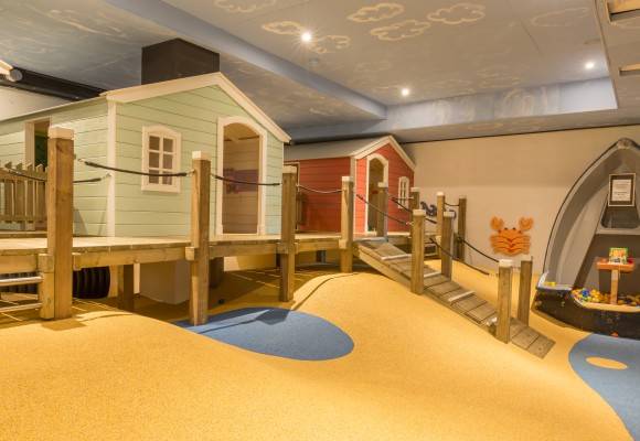 Kinderspielplatz im Strandpark De Zeeuwse Kust mit kleinen Häusern und einer Holzbrücke.