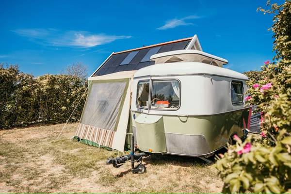 Camping-Wohnwagen mit Solarpanel auf dem Stellplatz.