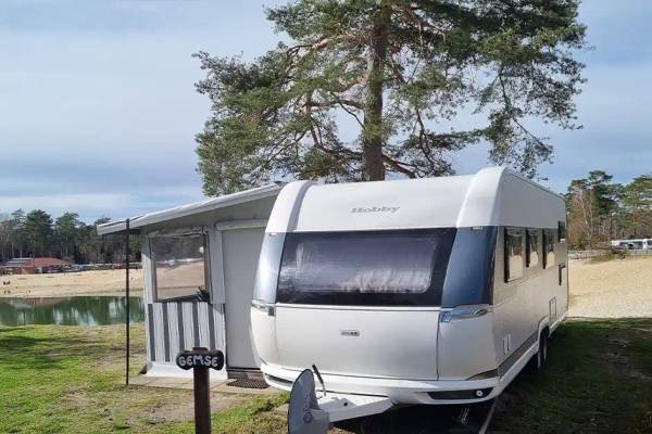 En hvid campingvogn parkeret på Südsee-Camp campingplads nær en sø.