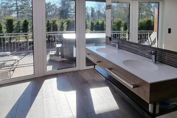 Badeværelse med terrasse og udsigt til haven, to vasker og en stor spejl.