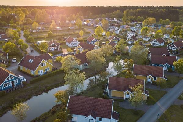 Luftfoto af Sudsee Camp camping med farverige huse og en flod.