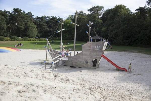 Piratenschiff-Spielplatz im Camping De Paal mit spielenden Kindern und einer Rutsche.