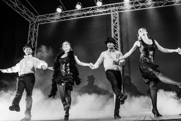 Foto en blanco y negro de un grupo de bailarines en el escenario con trajes vintage.