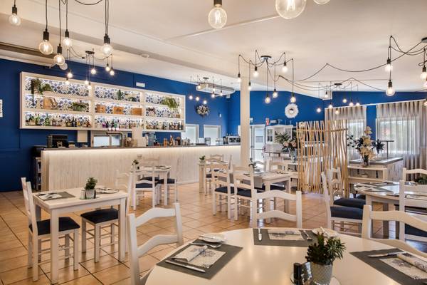 Interior del Turiscampo Camping Club Algarve con mesas y sillas blancas y paredes azules.