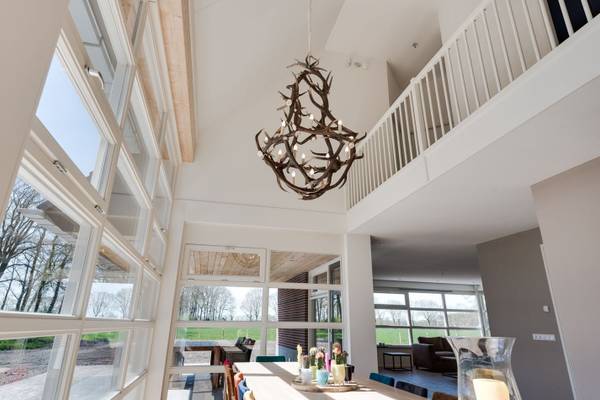 Indre udsigt af et feriehus med spisebord, lysekroner og balkon.