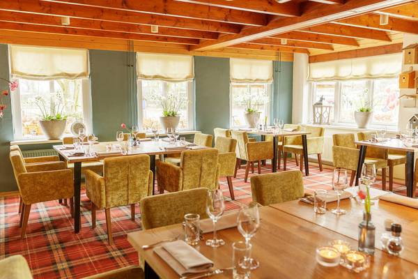 Indre udsigt af restaurantet på Vakantiepark De Twee Bruggen med træbjælker, grønne vægge og spisebord dækket med glas og blomster.