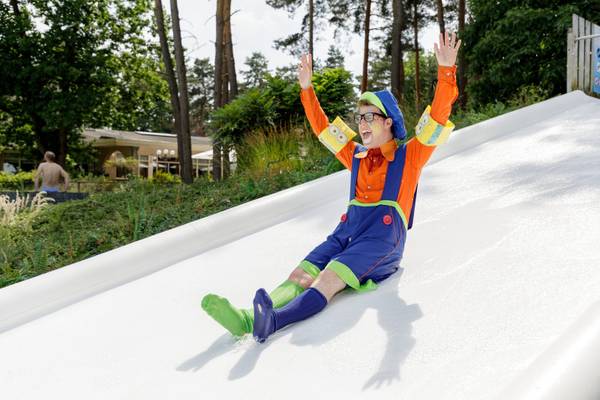 Person in Kostüm rutscht eine riesige Rutsche auf dem Campingplatz hinunter.