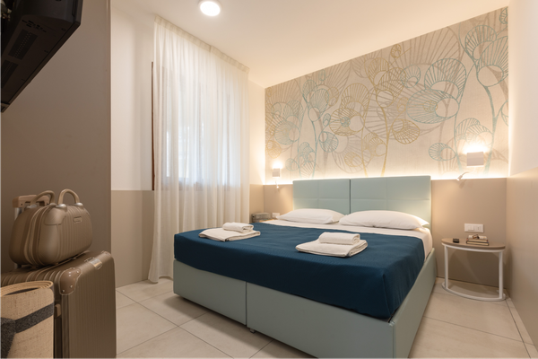 Slaapkamer met bed en decoratie, met een bed met blauwe lakens, kussens en decoratieve muurkunst.