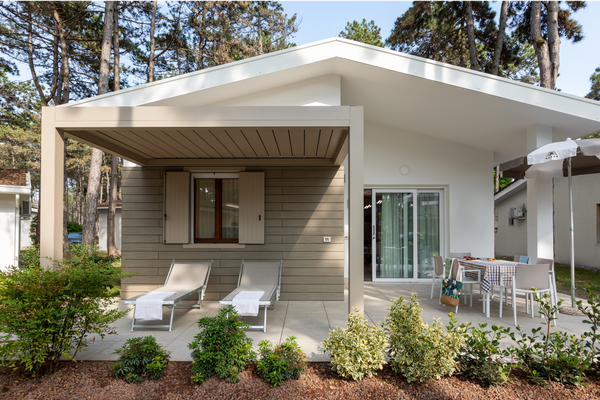 Camping Villaggio Turistico Internationale met een wit huis, twee ligstoelen en een eethoek buiten.