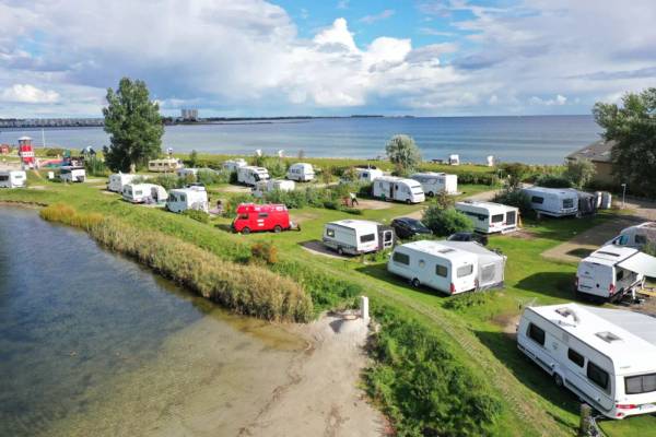Luftaufnahme des Campingplatzes Wulfener Hals am Meer mit vielen geparkten Wohnwagen und Autos.