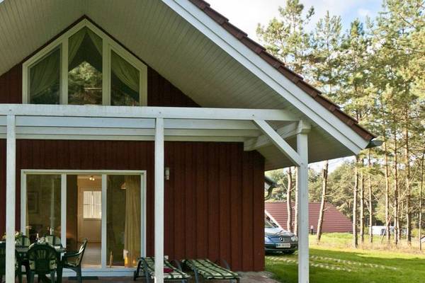 A red wooden chalet with a patio at Camping- und Ferienpark Havelberge.