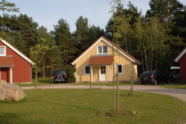 Three vacation homes at the Camping and Holiday Park Havelberge, surrounded by greenery and trees.