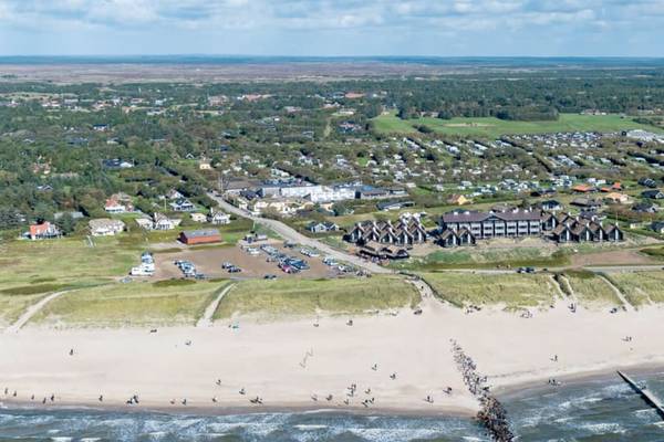 Luftaufnahme des Hvidbjerg Strand Ferieparks mit Gebäuden, Strand und Menschen.