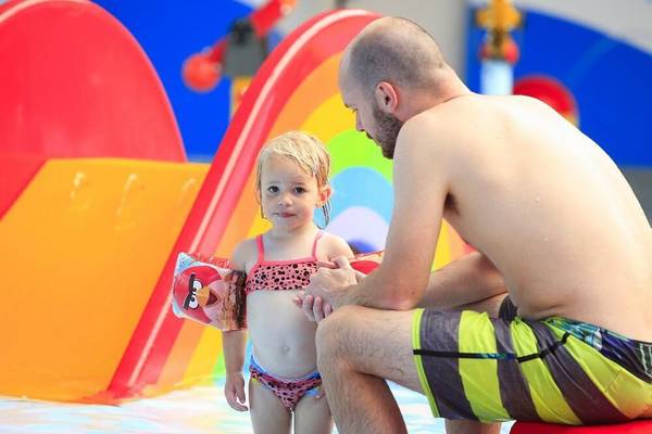 Ein Mann und ein kleines Mädchen sitzen in einem flachen Pool im Camping De Paal.