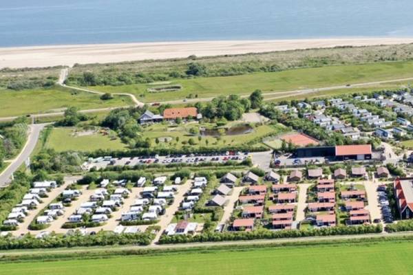 Luftaufnahme des Campingplatzes Strandpark De Zeeuwse Kust mit Gebäuden, Bäumen und Strand.