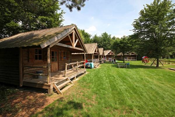 Eine Reihe von Holzhütten in einem Campingplatz mit grünem Gras und Bäumen.