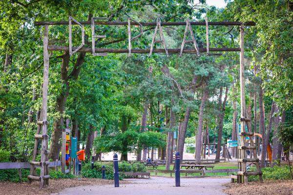 Eingang des Campingplatzes De Paal im Wald mit Holzbogen und Spielplatz