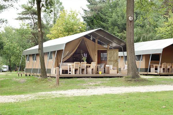 Een tent op Camping De Wildhoeve met houten meubels op een veranda