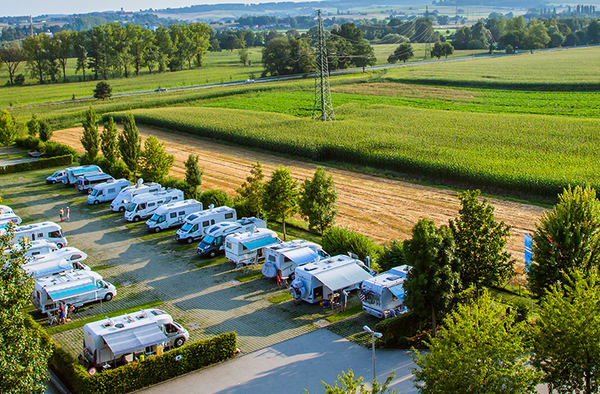 Vue aérienne d'un camping avec plusieurs camping-cars garés en rang.