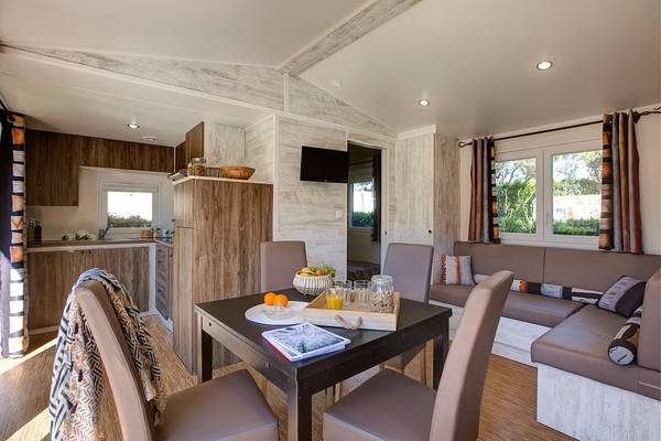 Intérieur du Camping Village Le Brasilia avec zone de repas, chaises et table.