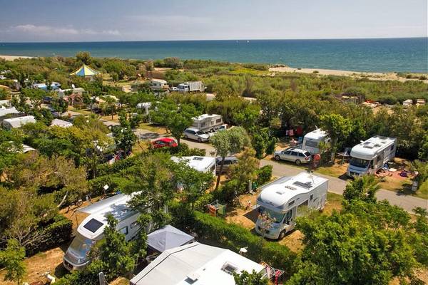 Vue aérienne du camping Village Le Brasilia près de l'océan avec plusieurs camping-cars et voitures garées.