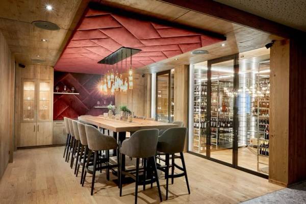 Innenansicht der Zugspitz Resort Camping Bar mit einem langen Holztisch und Weinkeller.