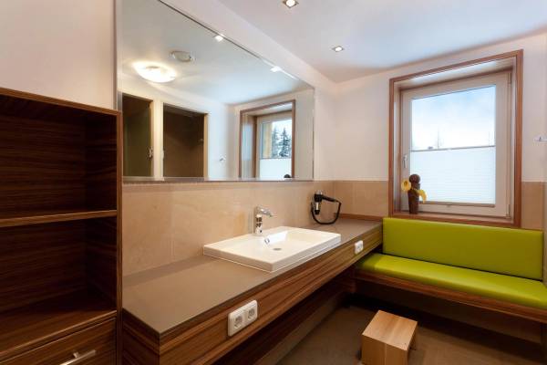 Innendesign eines Campingplatzbadezimmers im Zugspitz Resort mit Waschbecken, Spiegel und Bank