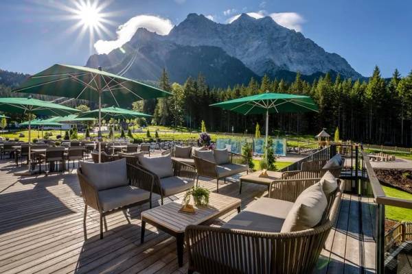 Terrasse im Zugspitz Resort mit Sonnenschirmen und Blick auf die Berge.