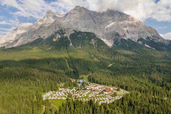 Luftaufnahme des Zugspitz Resort Campingplatzes mit Bergen im Hintergrund.