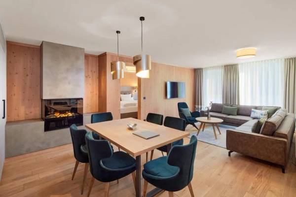 Zugspitz Resort Inneneinrichtung Wohnzimmer mit Holzboden, Kamin und moderner Möblierung.