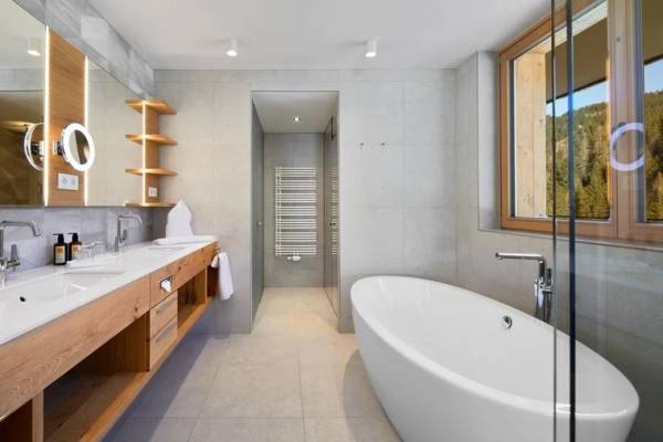 Badezimmer im Zugspitz Resort Campsite mit hölzernen Armaturen und einer Glasdusche.