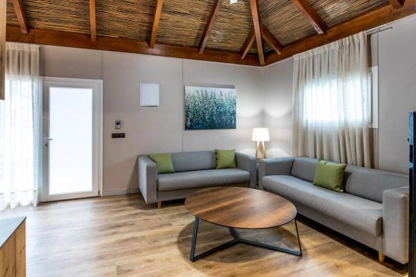 Intérieur salon au camping La Marina avec deux canapés gris, une table ronde en bois et une peinture.
