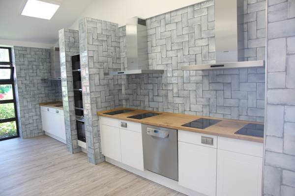 Küche mit Glasfliesen und Holzarbeitsplatte mit modernen Geräten.