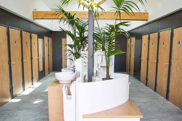Espace douche au Camping Le Pin Parasol avec portes en bois et lavabos