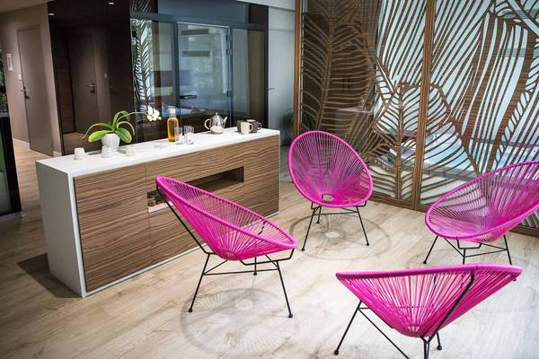 Espace intérieur du Camping Le Pin Parasol avec des chaises roses et une armoire en bois.