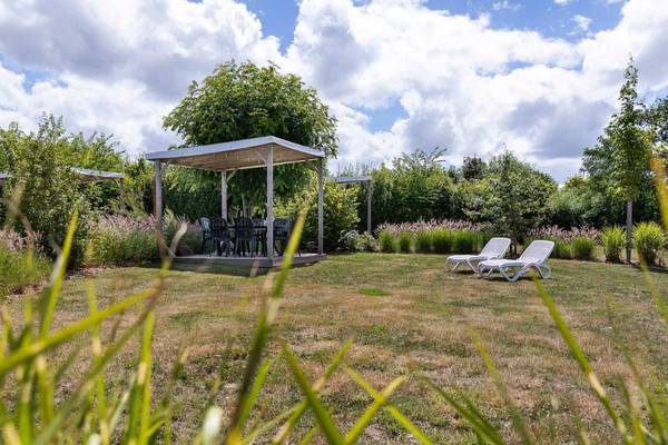 Espace de détente extérieur au Camping Le Pin Parasol avec une table et des chaises sous un gazebo.