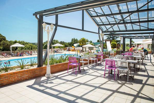 Terrasse avec tables et chaises au Camping Le Pin Parasol