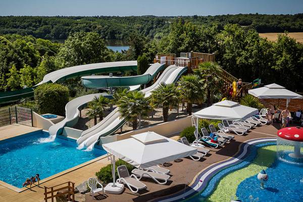Camping avec toboggans aquatiques, piscine et chaises longues sous parasols au Camping Le Pin Parasol.